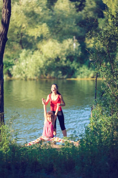 Aile egzersiz - anne ve kızı plajda egzersizleri yapıyor. — Stok fotoğraf
