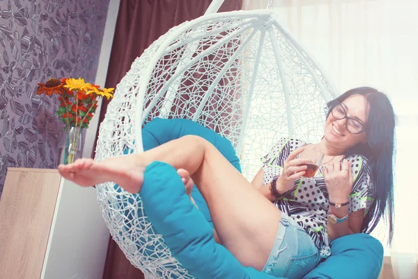 Jeune femme à la maison assise sur une chaise moderne devant la fenêtre r — Photo