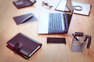 Bilgisayarı ve ahşap masasında akıllı telefonu olan bir ofis.