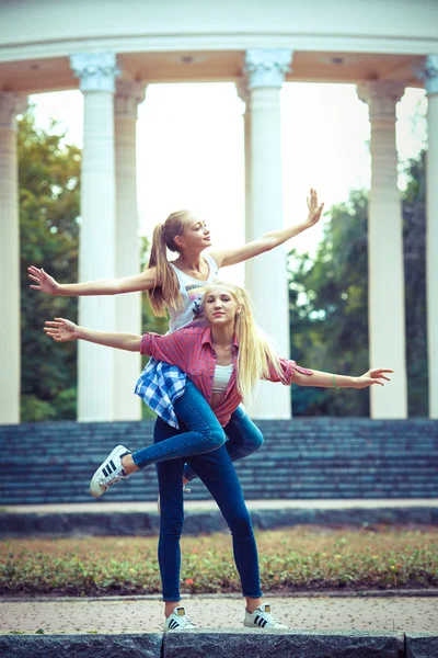 Twee jonge meisje vrienden samen in hug op park — Stockfoto