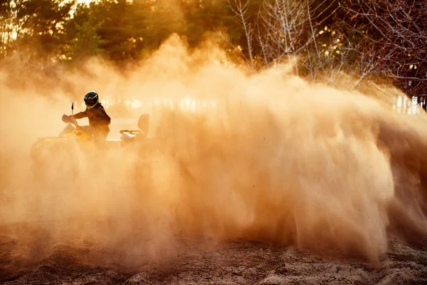 Teen riding ATV in sand dunes making a turn in the sand