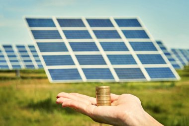 Arka planda fotovoltaik güneş enerjisi panelleri olan el ele tutuşma para banknotu, 