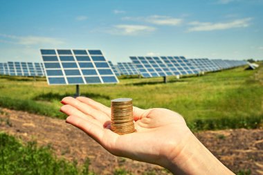 Arka planda fotovoltaik güneş enerjisi panelleri olan el ele tutuşma para banknotu, 