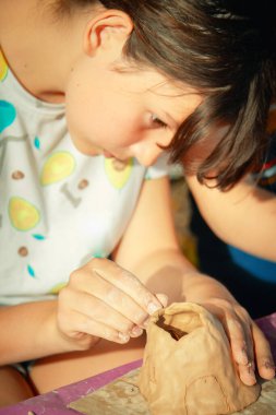 Çocuklar kille oynuyorlar ve boyalarla çiziyorlar..