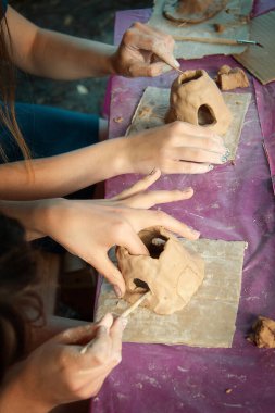 Çocuklar kille oynuyorlar ve boyalarla çiziyorlar..