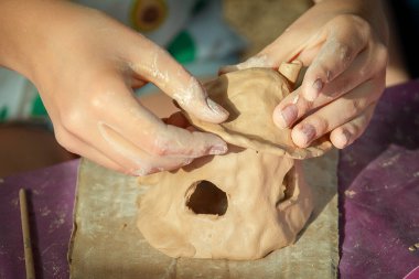 Çocuklar kille oynuyorlar ve boyalarla çiziyorlar..