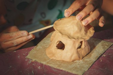 Çocuklar kille oynuyorlar ve boyalarla çiziyorlar..