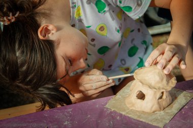 Çocuklar kille oynuyorlar ve boyalarla çiziyorlar..