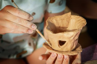 Çocuklar kille oynuyorlar ve boyalarla çiziyorlar..