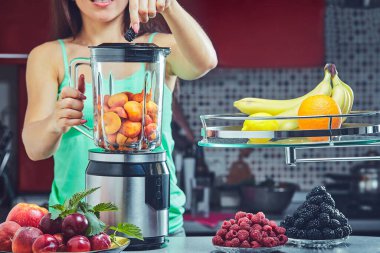 Kadın mutfak yeşil smoothie yapmak. Blender üzerinde odaklanmak.