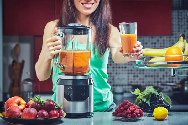 Woman making green smoothie on the kitchen. Focus on the blender.