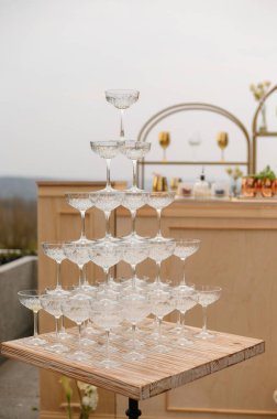 Dışarıdaki ahşap bir masada boş şampanya kadehleri piramidi..