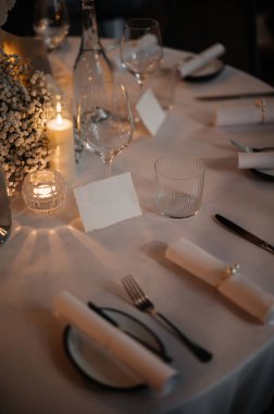 Mumlar, cam eşyalar ve isim kartlarıyla şık bir masa..