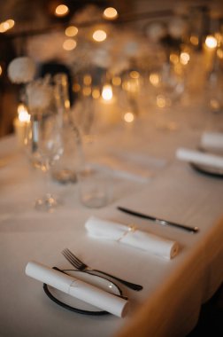 Yuvarlak peçeteli ve loş ışıklandırmalı zarif bir masa..