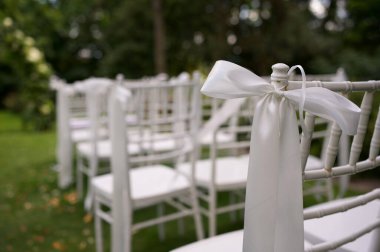 Açık hava düğün töreni için kurdeleli beyaz sandalyeler..