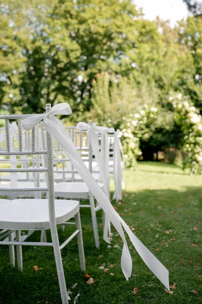 Beyaz sandalyeler ve kurdelelerle kurulmuş açık hava düğün töreni..
