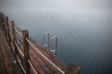 Göl kenarı sisli, tahta korkuluklu ve metal merdivenli. Zakrzowek, Krakow