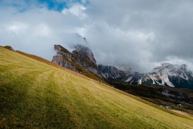 İtalyan Dolomitleri 'ndeki Seceda dağ sırtlarının geniş bir görüntüsü, yemyeşil çayırlar sisli tepelere doğru yol alıyor.