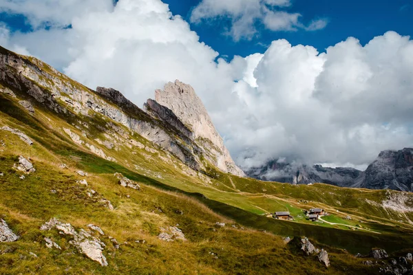 Dramatik bulutlar, İtalya 'nın Dolomitlerin yeşil dağlık çayırlarına kurulmuş ikonik Seceda dağ sırtları ve geleneksel ahşap kulübelerin üzerinde toplanıyor.