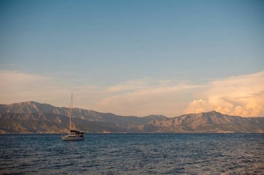 Yalnız bir yelkenli Adriyatik Denizi 'nin sakin, mavi sularında süzülüyor. Arka planda görkemli bir dağ sırası var.