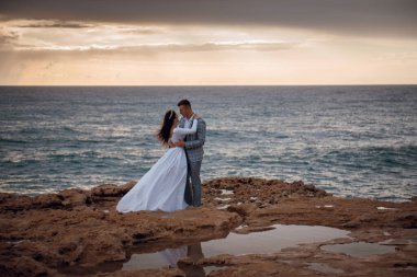 Bir gelin ve damat, düğün günlerinde Kıbrıs 'ın kayalık kıyılarında hassas bir anı paylaşıyor