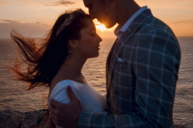 Bir gelin ve damat, Kıbrıs 'ta romantik bir gün batımı seremonisi sırasında denize bakan bir uçurumda hassas bir anı paylaşıyor.