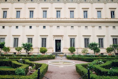 Roma, İtalya 'daki tarihi Borghese Galerisi önünde manikürlü çitleri ve çeşmesi olan resmi bir bahçe.