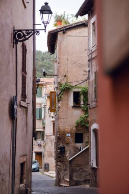 İtalya 'nın Tivoli şehrinde tarihi binalar ve eski moda bir sokak lambasıyla çevrili tuhaf, dar bir kaldırım taşı caddesi.