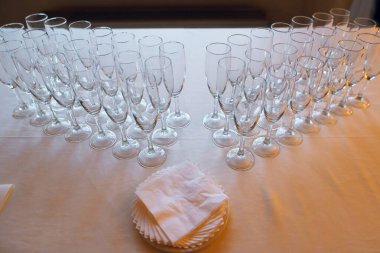 Sayısız temiz şampanya bardağının kullanılmaya hazır olduğu bir kutlama için hazırlanmış resmi bir ortam. Yanında da temiz kağıt peçeteler.