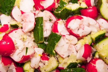 Dilimlenmiş turplu ve yağlı ve baharatlı salatalı taze bir salata. Parlak pembe turplar ve yeşil salatalık iştah açıcı bir kompozisyon oluşturur..