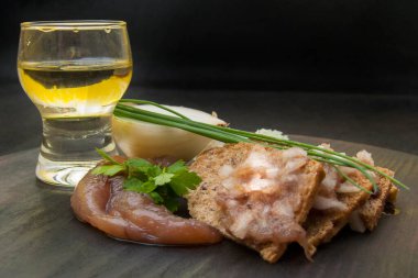 Bir shot votka, çavdar ekmeği, havyar ve taze otlarla özgün bir kompozisyon. Dramatik ışıklandırma geleneksel kırsal tarzda bir yemeğin dokusunu vurgular..