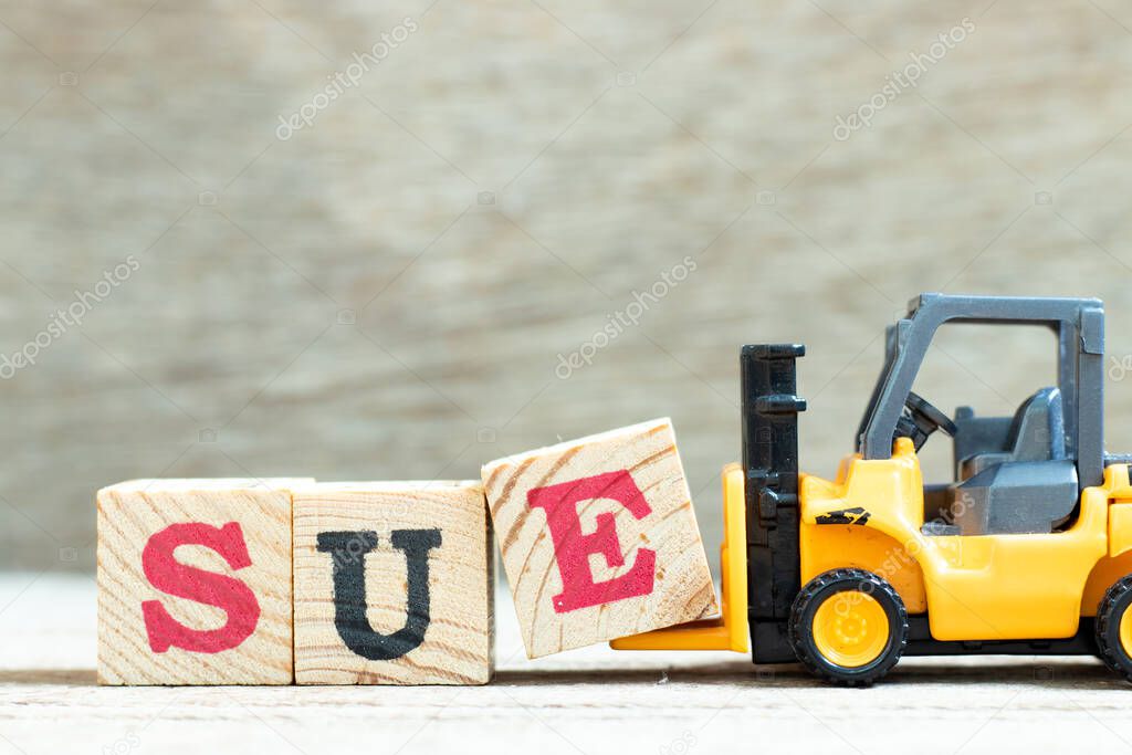 Toy forklift hold letter block e to complete word sue on wood background