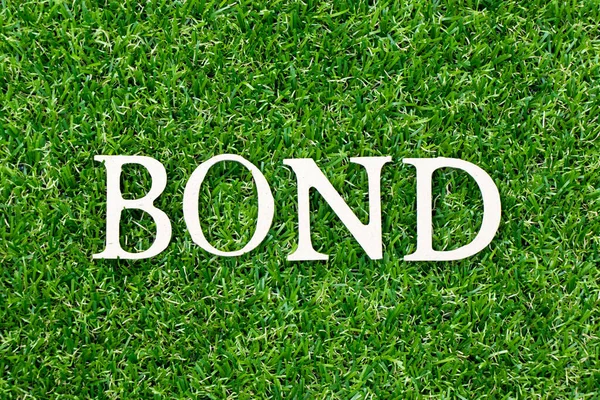 Wood letter in word bond on green grass background