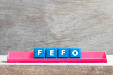 Kelime FEFO 'sunda kırmızı rafta yer alan döşeme harfi (ilk kez kullanım tarihi geçmiş) ahşap arkaplanda