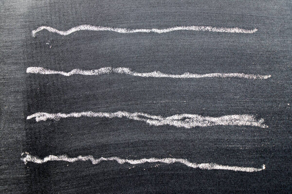 White color chalk hand drawing in set of wavy line shape on black board background