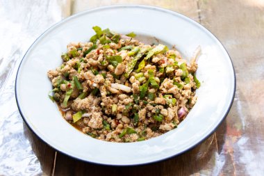 Tahta arka planda Tayland yemeği baharatlı kıymalı domuz salatası.