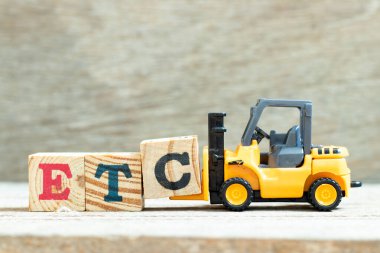 Oyuncak forklift, ahşap arkaplan üzerinde kelime tamamlamak için c harfi blok vs. (vs. kısaltması) tutun