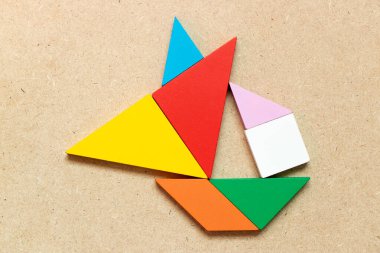 Ahşap zemin üzerinde yelkenli teknesi şeklindeki renk tangramı (Girişimci ya da iş kurma kavramı)