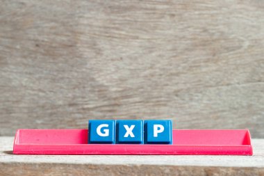 Harf kırmızı rafta tahta zemin üzerinde GXP ile yazılıyor.