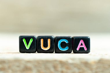 Tahta zemin üzerinde VUCA (uçuculuğun kısaltması, belirsizlik, karmaşıklık ve belirsizlik) sözcüğüyle siyah renk bloğu