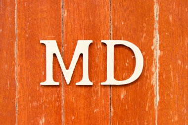 Doktorun kısaltması olan MD harfiyle alfabe harfi eski kırmızı tahta arka planda.