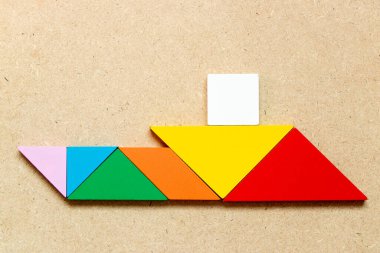 Ahşap zemin üzerinde yelkenli teknesi şeklindeki renk tangramı (Girişimci ya da iş kurma kavramı)