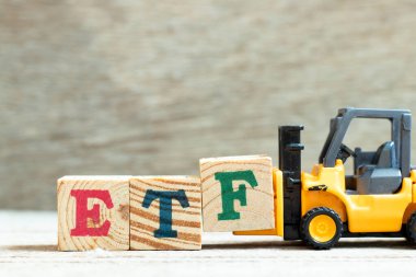 Ahşap zemin üzerinde ETF (Borsa Fonu kısaltması) sözcüğünü tamamlamak için oyuncak kaldırma engeli