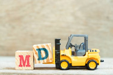 Toy forklift, ahşap arka planda MD sözcüğünü tamamlamak için d harfi engeli (tıp doktorunun kısaltılmışı veya genel müdür)