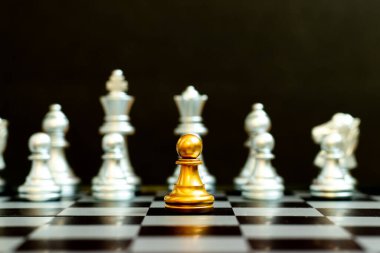 Satranç oyununda altın piyon siyah zemin üzerinde diğer gümüş takım ile birlikte (Şirket stratejisi, iş zaferi veya karar kavramı)
