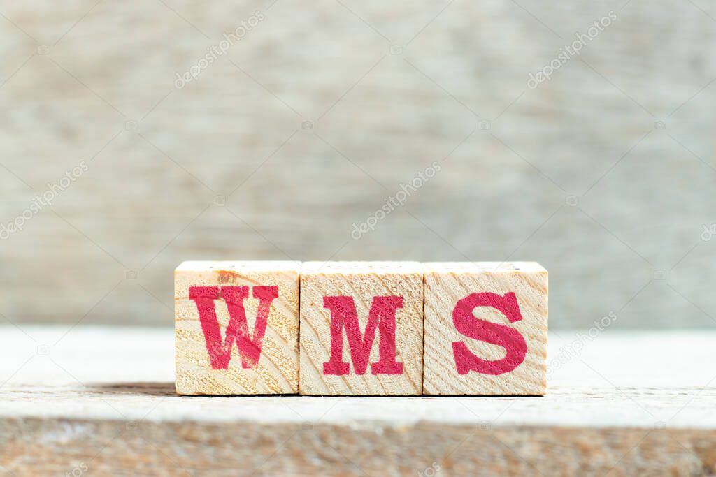 Alphabet letter block in word WMS (Abbreviation of warehouse management system) on wood background