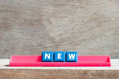 Ahşap arkaplanda yeni sözlerle kırmızı raftaki döşeme harfi