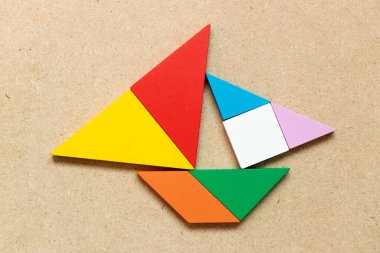 Ahşap zemin üzerinde yelkenli teknesi şeklindeki renk tangramı (Girişimci ya da iş kurma kavramı)