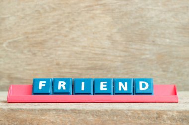 Ahşap arkaplanda kırmızı renk rafında arkadaş sözcüğüyle harf döşemesi