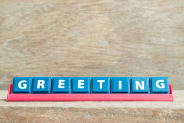 Ahşap arkaplanda kırmızı renk rafında kelime karşılama içeren döşeme alfabesi harfi